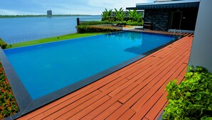 A swimming pool with a wooden deck, surrounded by a low fence and a flower bed. - Kent Baywatch Suites (Kochi)