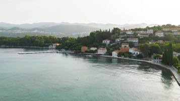 Un poble costaner amb edificis al passeig marítim, una platja de sorra i una vista clara del mar.