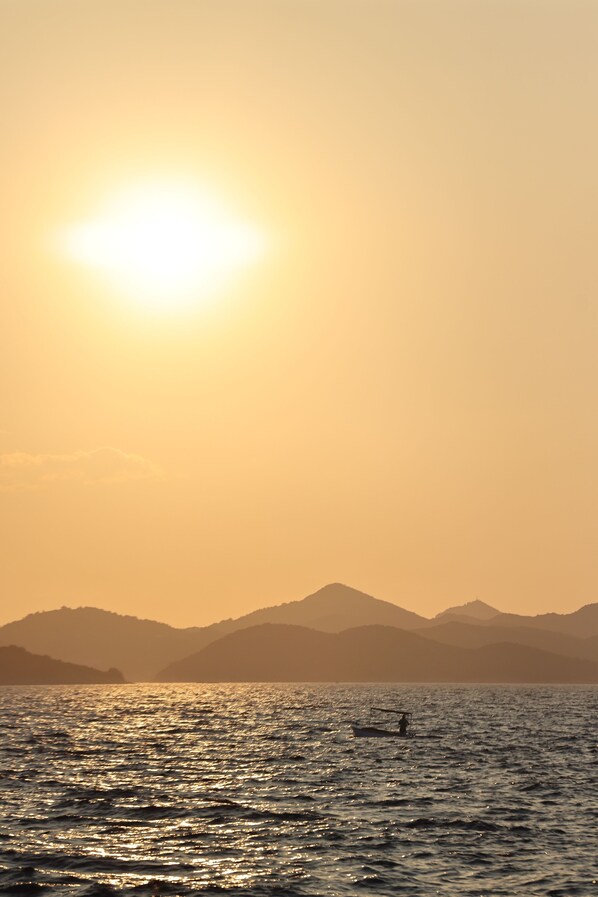 Un atardecer sobre un cuerpo de agua con montañas al fondo.