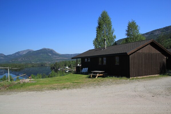 A cabin by a lake with a picnic table and chairs, surrounded by mountains. - Vrådal Hyttegrend (Kviteseid)