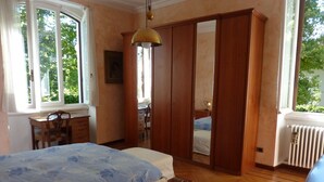 A bedroom with a bed, a desk, a chair, a wardrobe, and a radiator.