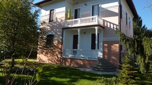 A two-story house with a balcony, a front porch, and a stone foundation.