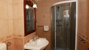 A bathroom with a glass-enclosed shower, a sink, and a mirror. - Hotel Zefir (Timisoara)