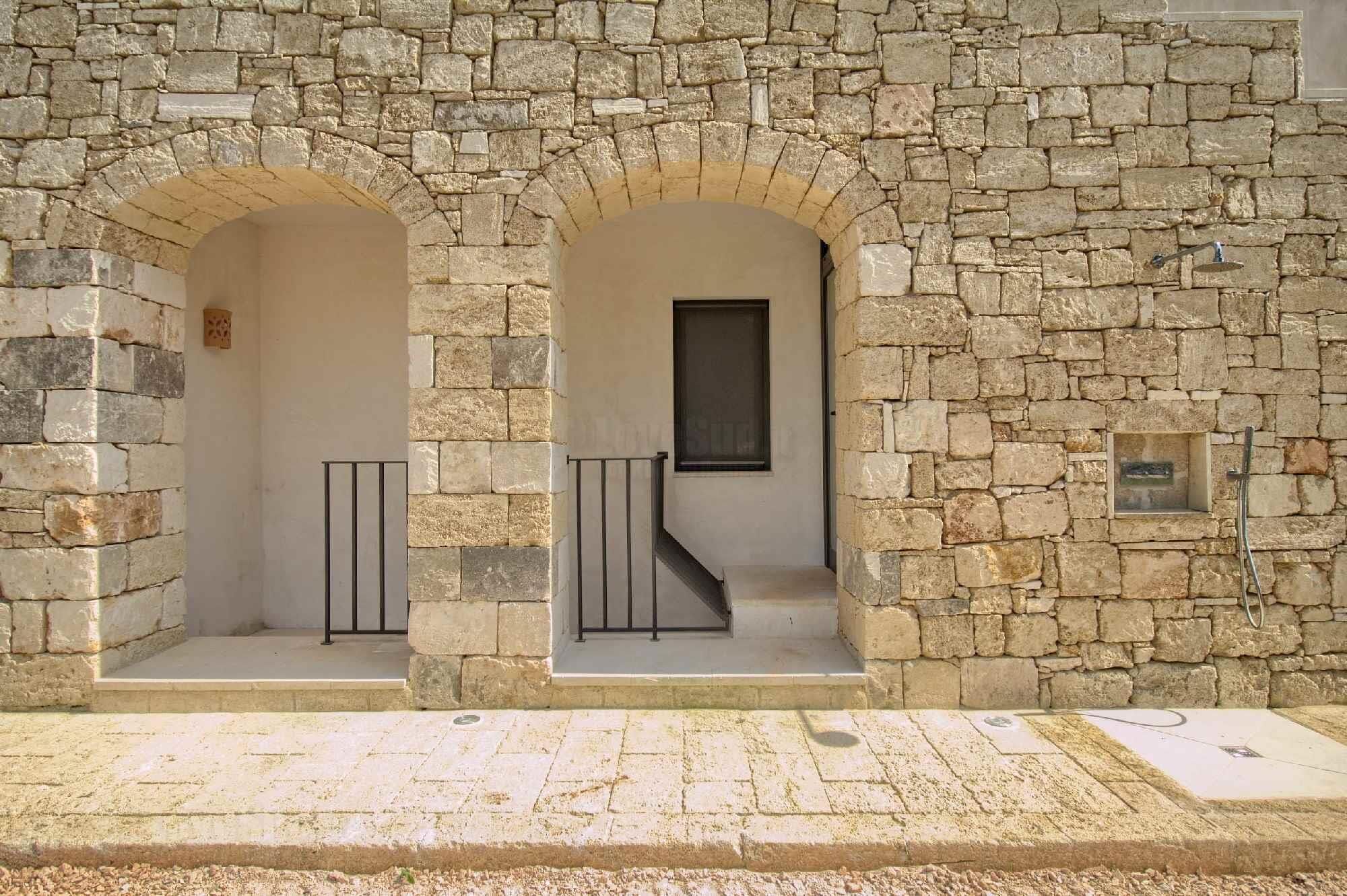 A stone building with two arched doorways, a small window, and a metal railing.