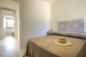 Ein Schlafzimmer mit einem Bett, einem Hut auf dem Bett, einem Nachttisch und dekorativen Wandverkleidungen.