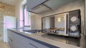 Una cocina moderna con estufa integrada, microondas y un amplio ventanal.