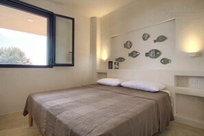 Une chambre à coucher avec un lit, des oreillers, une fenêtre et des décorations murales représentant des poissons.