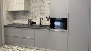 Una cocina moderna con armarios grises, encimera negra, microondas integrado y un salpicadero decorativo.
