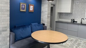 Una cocina moderna con armarios grises, una mesa redonda de madera y una pared azul decorada con marcos de fotos.