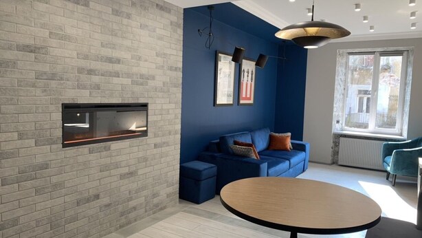 Una sala de estar moderna con pared de ladrillo, una pared azul de acento y una mesa redonda de madera.