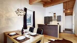 Een eetgedeelte met een houten tafel gedekt voor vier personen, een kroonluchter en een kussen van runderleer.