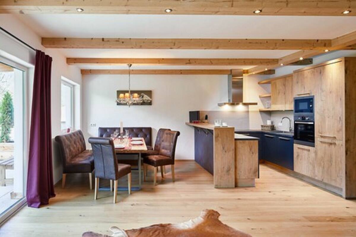 Una cocina moderna con vigas de madera, un área de comedor con sillones de cuero y vistas amplias a través de grandes ventanales.