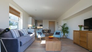A modern living room with a sofa, coffee table, and TV. - Sea Scapes – Sleeps 2/4 – Sea Views – Dog-Friendly - On-Site Parking (St Ives)