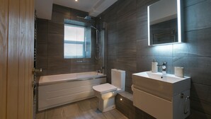 A modern bathroom with a bathtub, toilet, and vanity. - Sea Scapes – Sleeps 2/4 – Sea Views – Dog-Friendly - On-Site Parking (St Ives)
