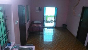 A small room with a bed, a window, and a door leading to an outdoor area. - serenity beach house (puducherry)