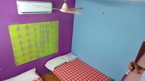 A room with two beds, a ceiling fan, and an air conditioner. - serenity beach house (puducherry)