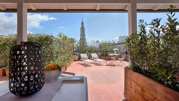 A covered patio with a view of a tower, lounge chairs, a planter, and a table. - Casa Pacifico (Pompei)