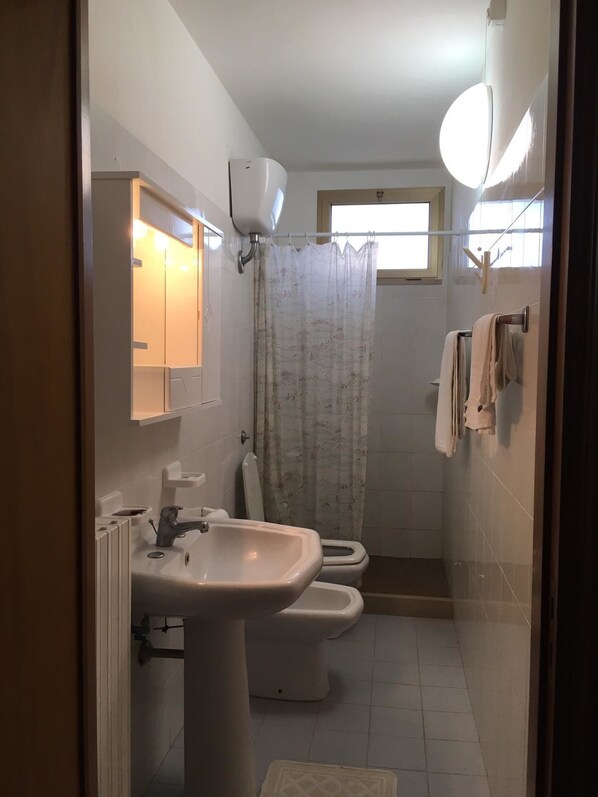 Un baño con lavamanos, inodoro y cortina de ducha.