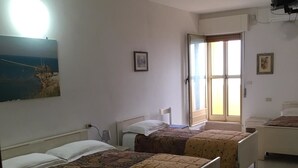 Een kamer met twee bedden, een groot raam en een plafondventilator.