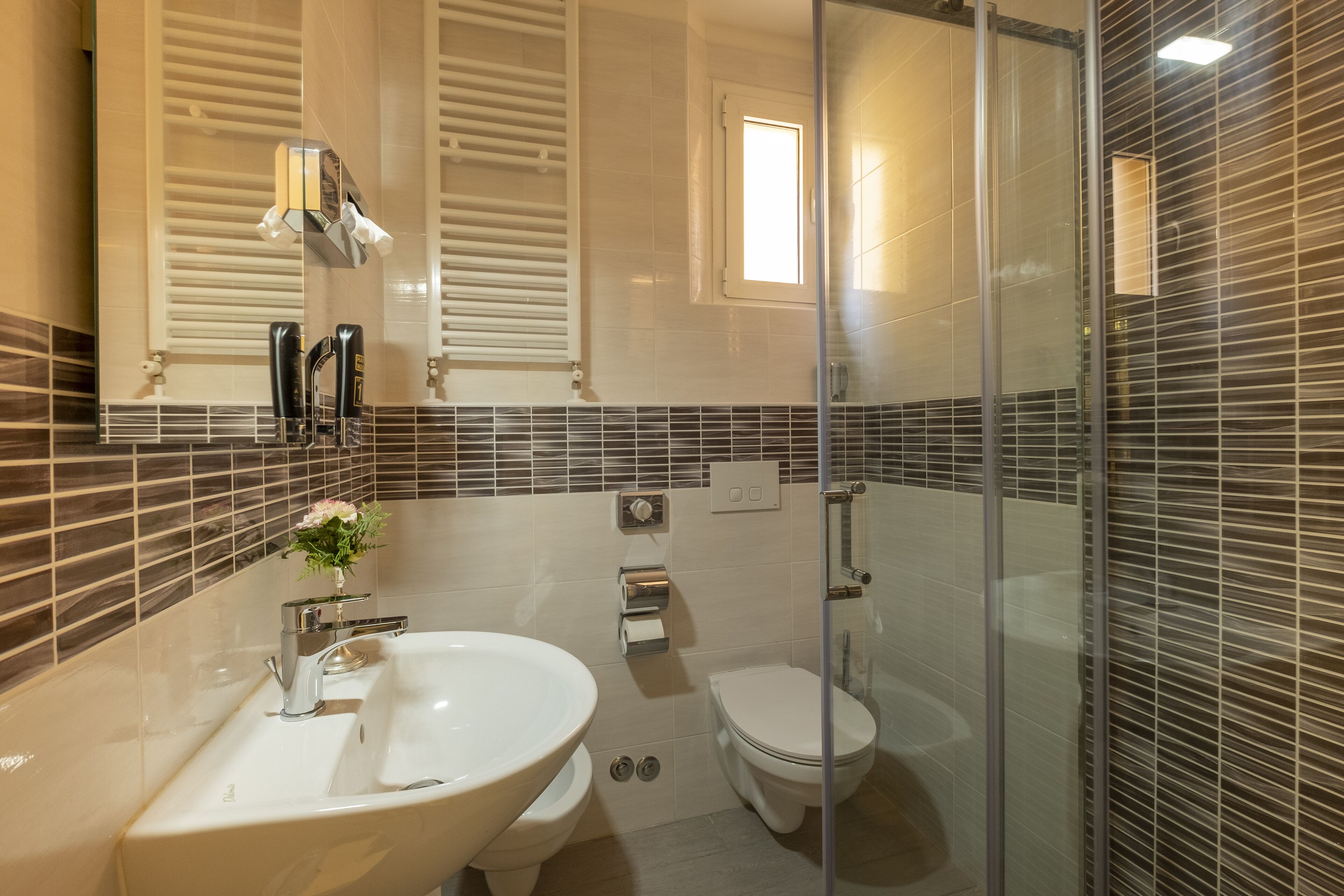 Un baño moderno con cabina de ducha de vidrio, un lavabo blanco y un inodoro.