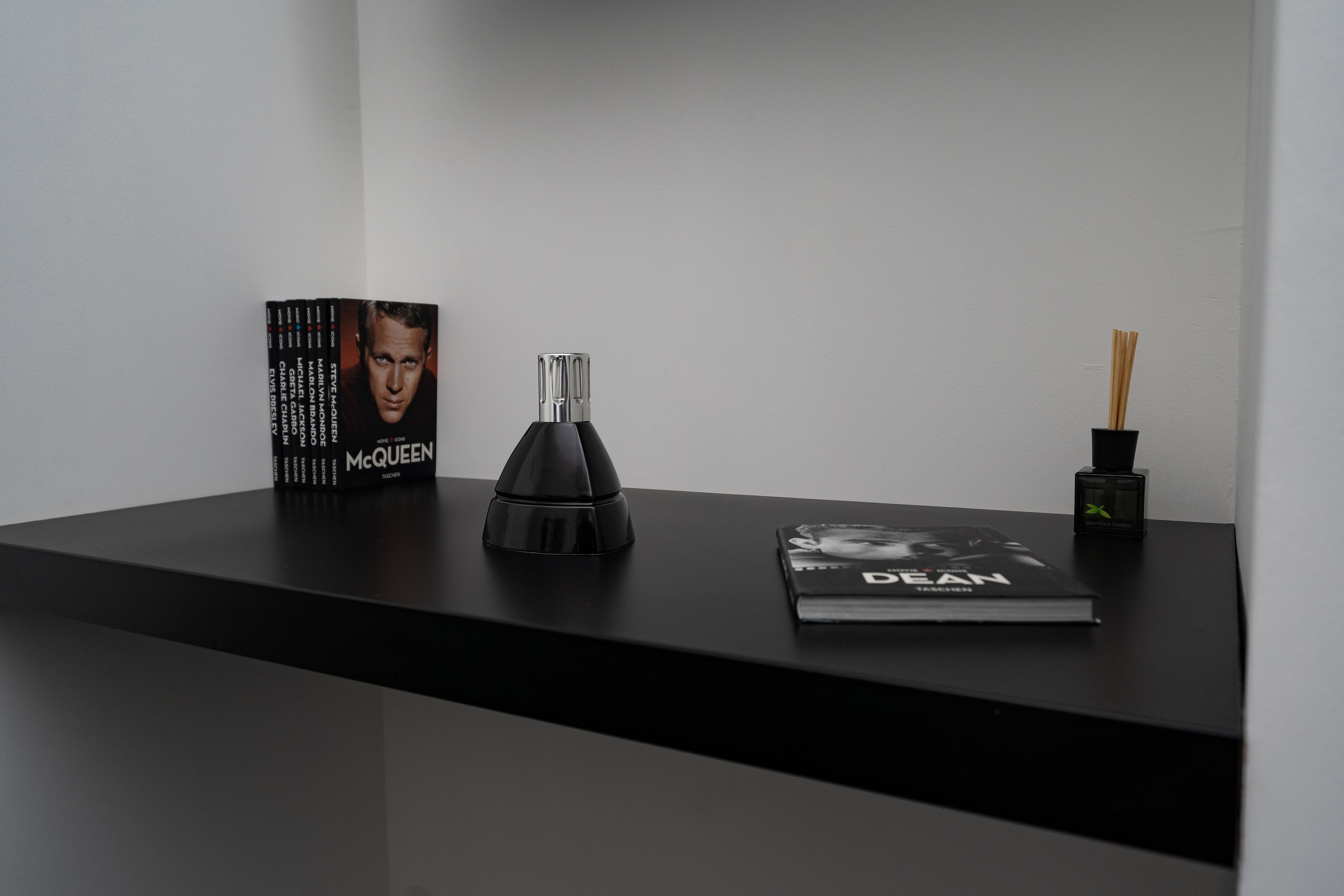 A black table with a book titled 'McQUEEN', a black object, and a book titled 'DEAN'.