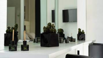 Une cuisine moderne avec un plan de travail blanc, des jardinières carrées noires contenant des cactus et une poubelle noire.