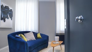 Una sala de estar moderna con un sofá azul, una mesita de madera y un florero blanco.