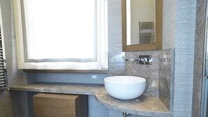 Un baño moderno con lavamanos integrado, un espejo y un ventanal.