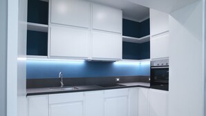 Una cocina moderna con armarios blancos, encimera negra y salpicadero azul.