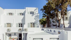 Un edificio blanco con varios balcones, un área de estar cubierta al aire libre y una escalera que conduce a un nivel superior.