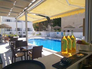 A poolside area with a bar, seating, and umbrellas.