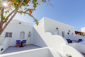 A white building with a balcony, a table, and two chairs.