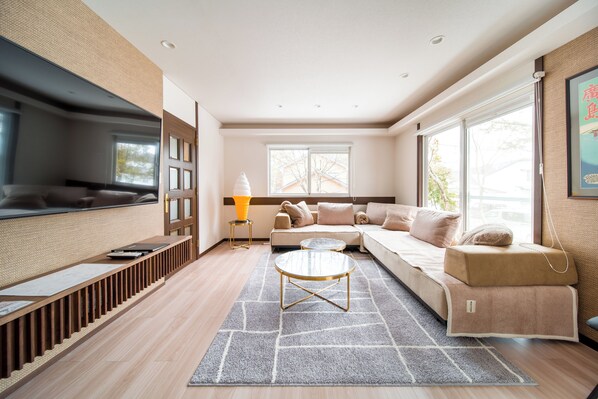 A modern living room with a sofa, a coffee table, and a TV. - Yama House Hakuba (Hakuba)