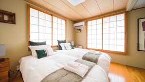 A hotel room with two beds, a wooden floor, and large windows. - Yama House Hakuba (Hakuba)