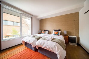 A hotel room with a large bed, a window, a heater, and a view of a building outside. - Yama House Hakuba (Hakuba)