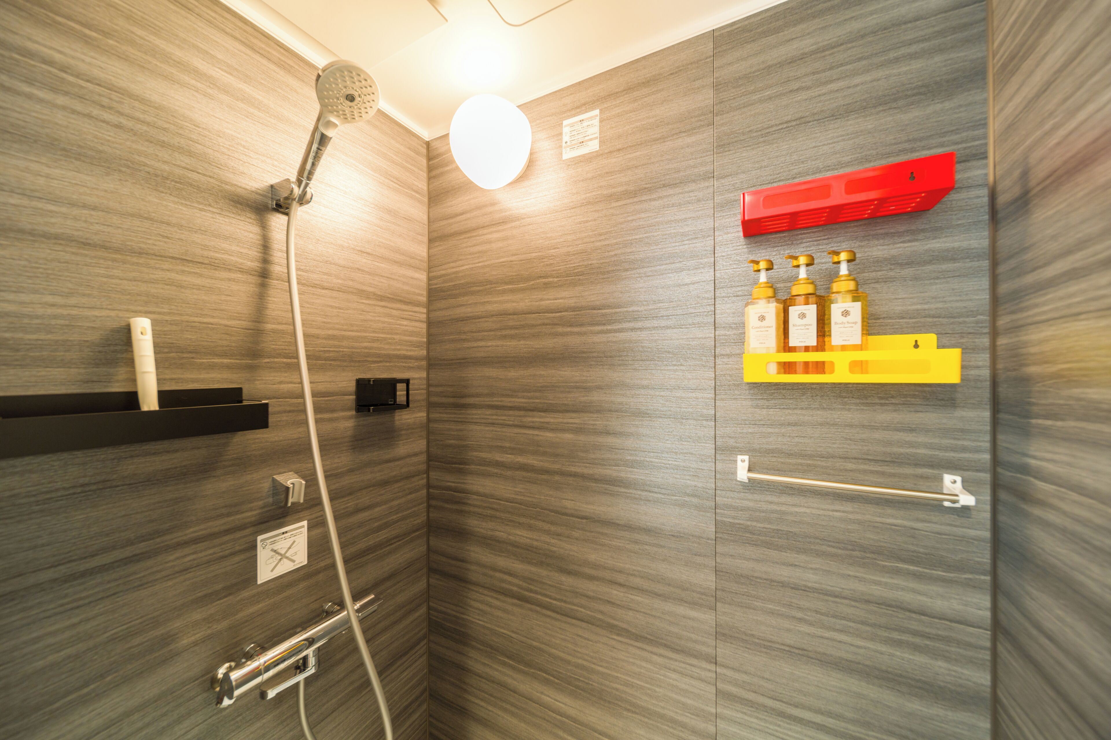 A modern bathroom with a shower, a towel rack, and a shelf with toiletries.