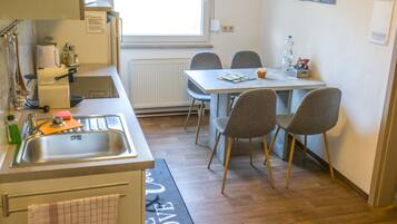 Una cocina compacta con un lavamanos, una ventana y una zona de comedor con sillas.