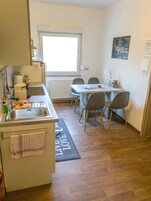 Una cocina compacta con un lavamanos, una ventana y una zona de comedor con sillas.