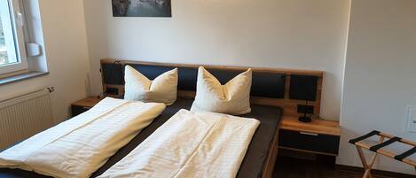 A neatly made bed with two pillows, a bedside table with a lamp, and a wall-mounted picture.