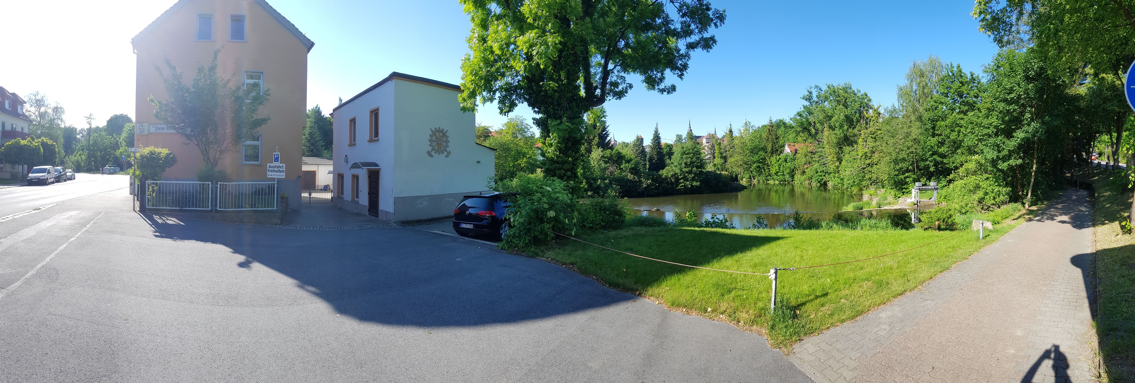 Ein Gebäude mit Parkschild, Teich und einem Weg.