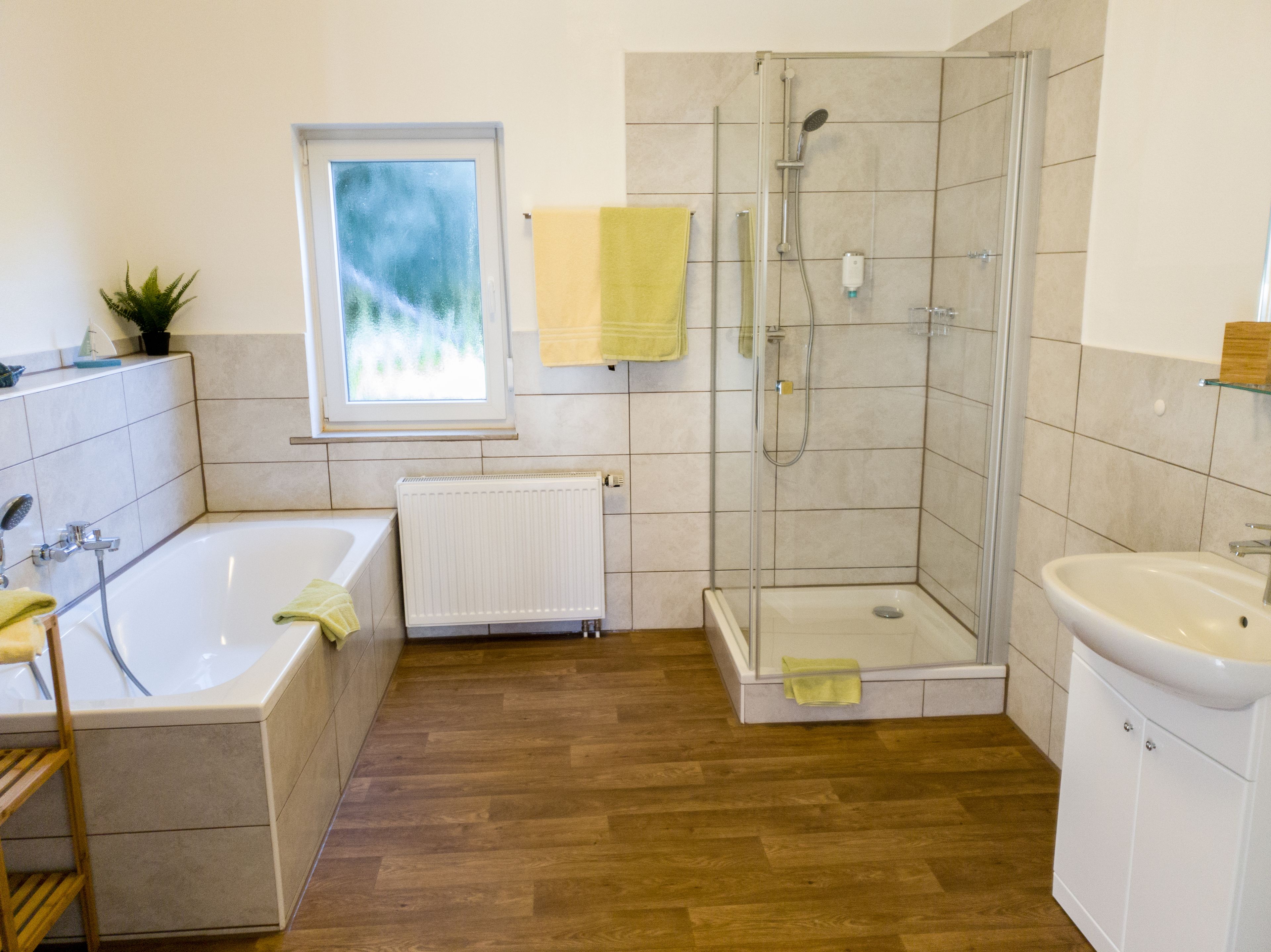 A modern bathroom with a bathtub, shower, and sink.