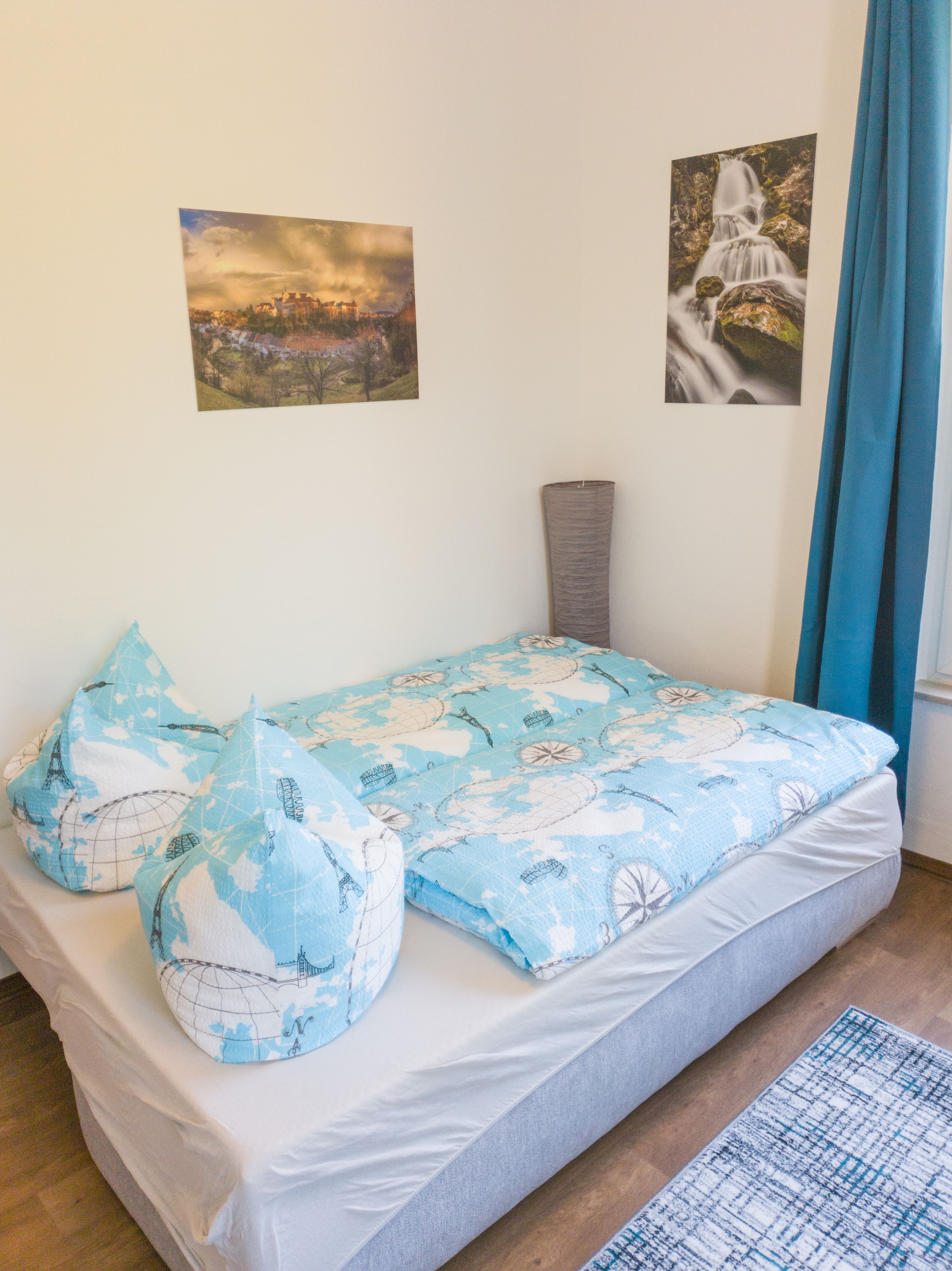 Ein Schlafzimmer mit einem Bett, Kissen, einer Lampe und zwei Bildern an der Wand.