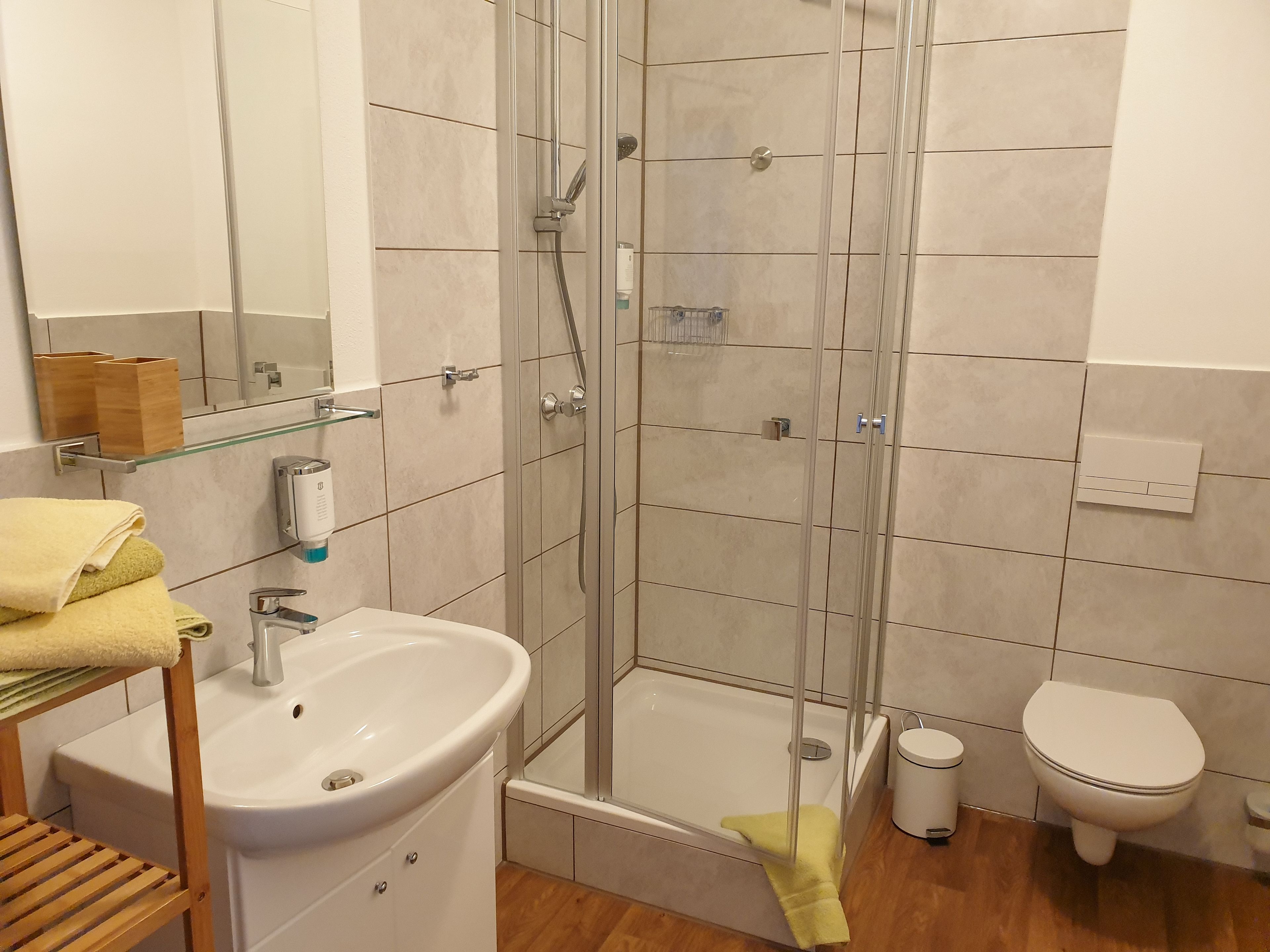 Un baño moderno con ducha de vidrio, lavamanos, inodoro y espejo.