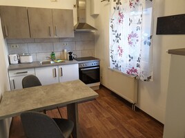 Una cocina compacta con una mesa de comedor, estufa y pileta.