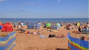 Una playa concurrida con sombrillas de colores y gente disfrutando.