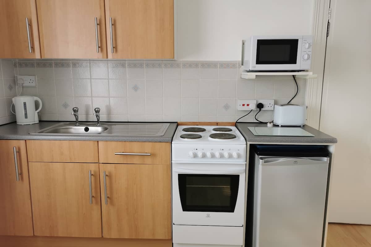 A kitchen with wooden cabinets, a stainless steel sink, a white stove, a microwave, and a dishwasher.