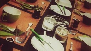 Una mesa de comedor con platos, tazones, vasos y cubiertos.