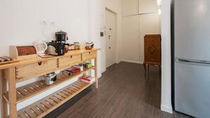 Una cocina con una mesa de madera, una cafetera y un refrigerador.