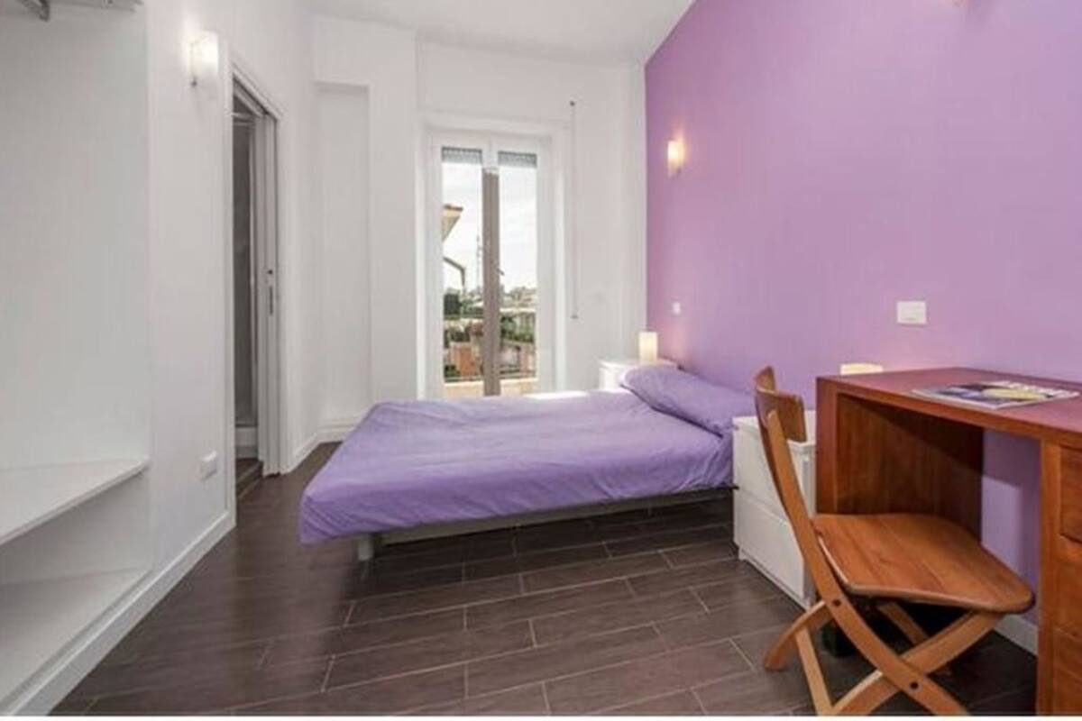 A bedroom with a bed, a desk, and a chair.