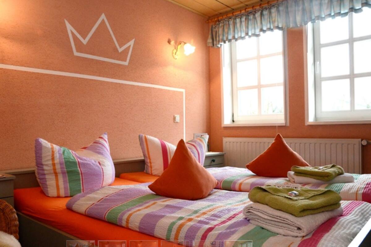 A room with a bed, pillows, a radiator, and a window.